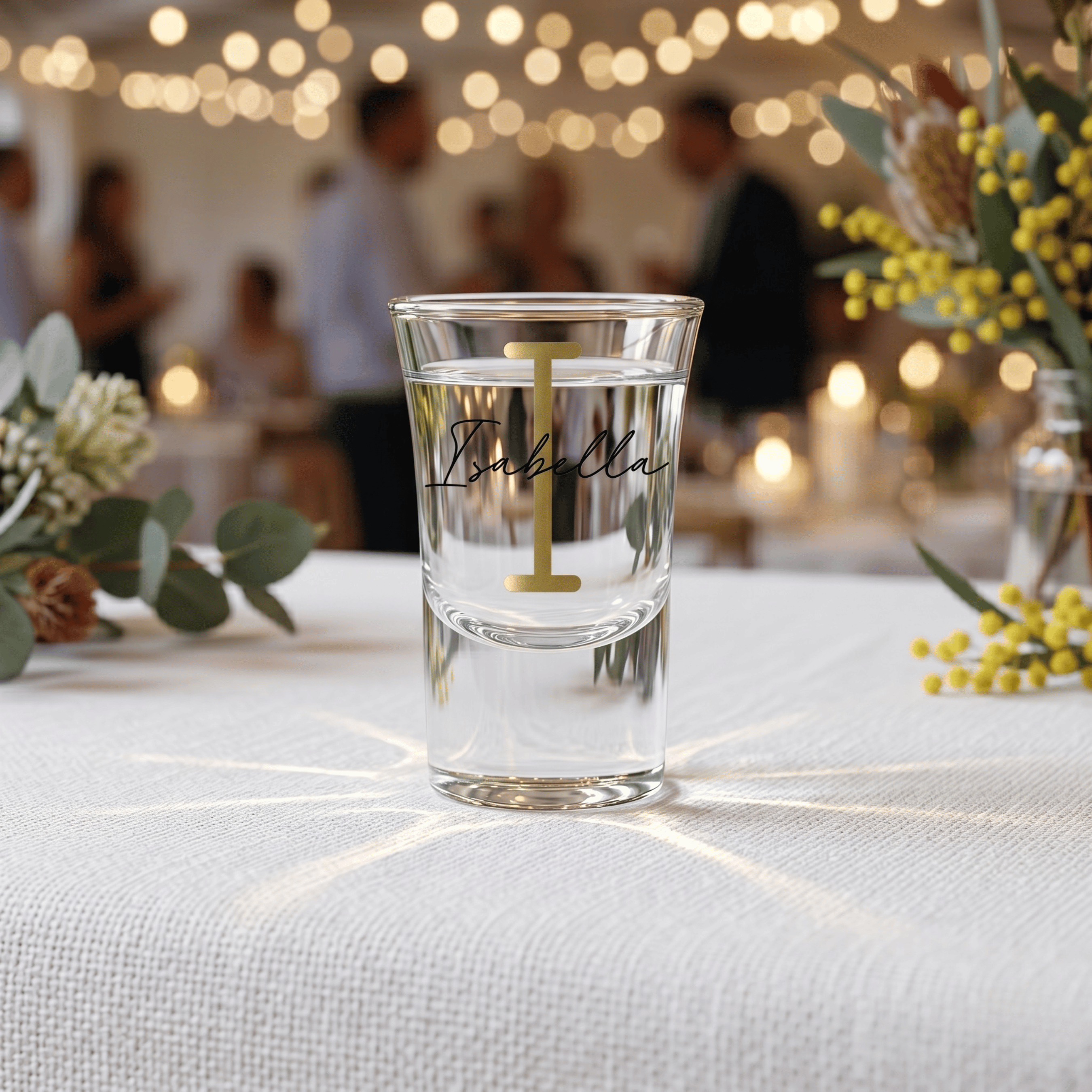 Clear glass with 'Isabella' and a number on a table with blurred background