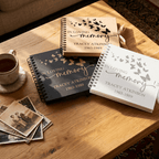 Three 'In Loving Memory' books on a wooden table with a cup of coffee and old photos.