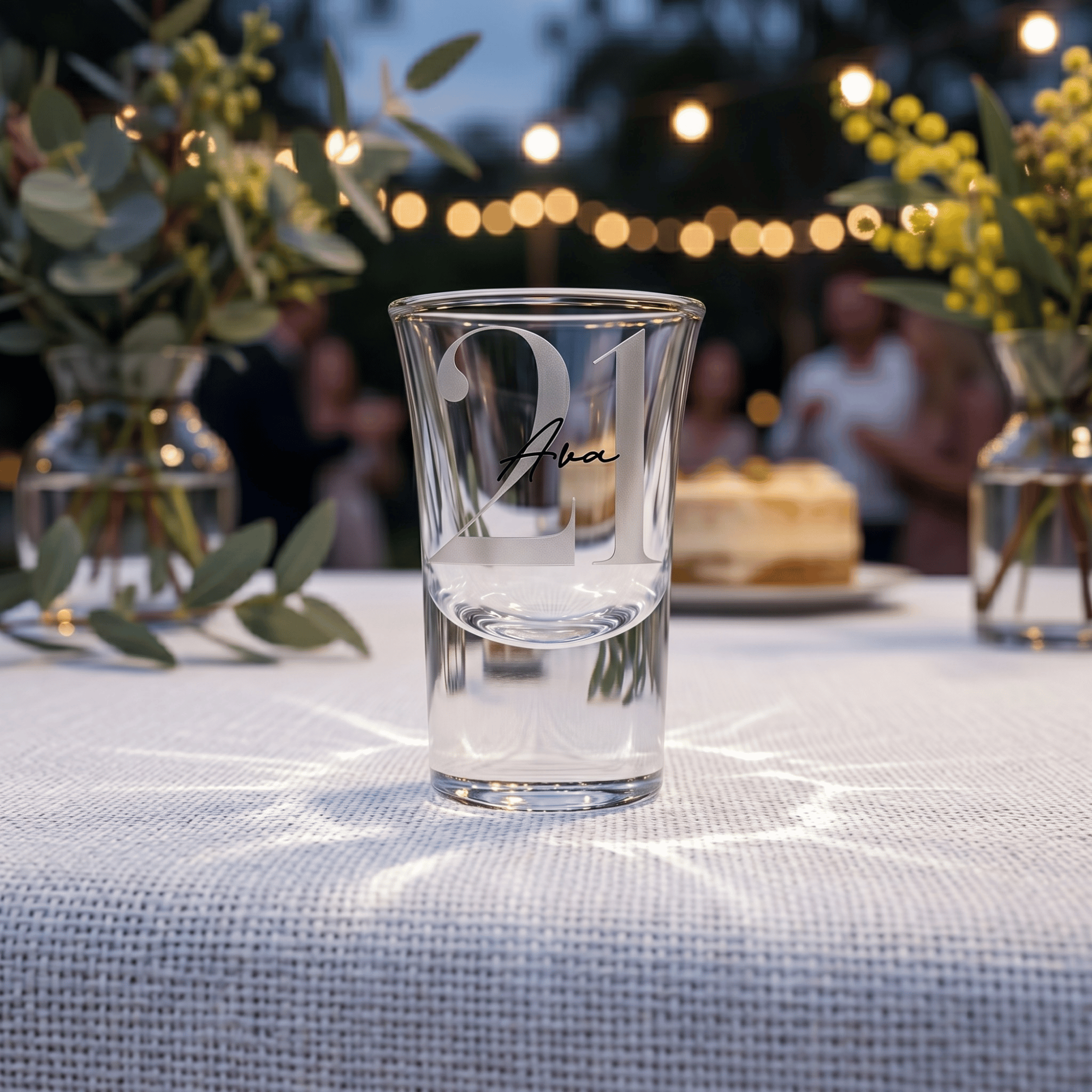 Clear glass with engraved text on a table with blurred background of people and lights