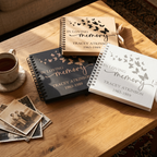 Three 'In Loving Memory' books on a wooden table with a cup of coffee and old photos.