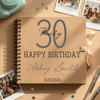 Personalised birthday album with '30 Happy Birthday Abbey Smith' on a wooden surface with photos and a camera.