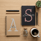 Two notebooks with personalized initials on a wooden surface with stationery items.