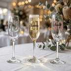 Three champagne flutes with personalized names on a table with a blurred festive background