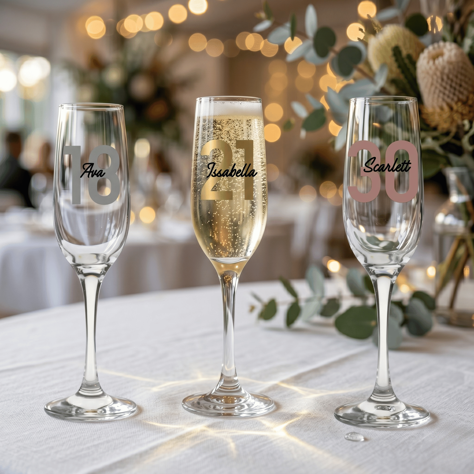 Three champagne flutes with personalized names on a table with a blurred festive background