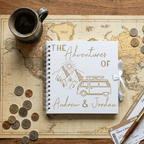 Personalised travel journal titled 'The Adventures of Andrew & Jordan' on a world map with coins and a mug.