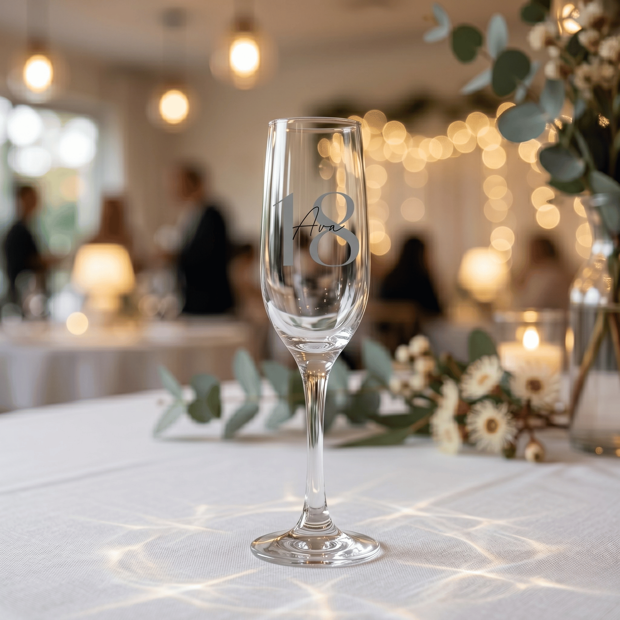 Champagne flute with '18' engraving on a table with blurred background