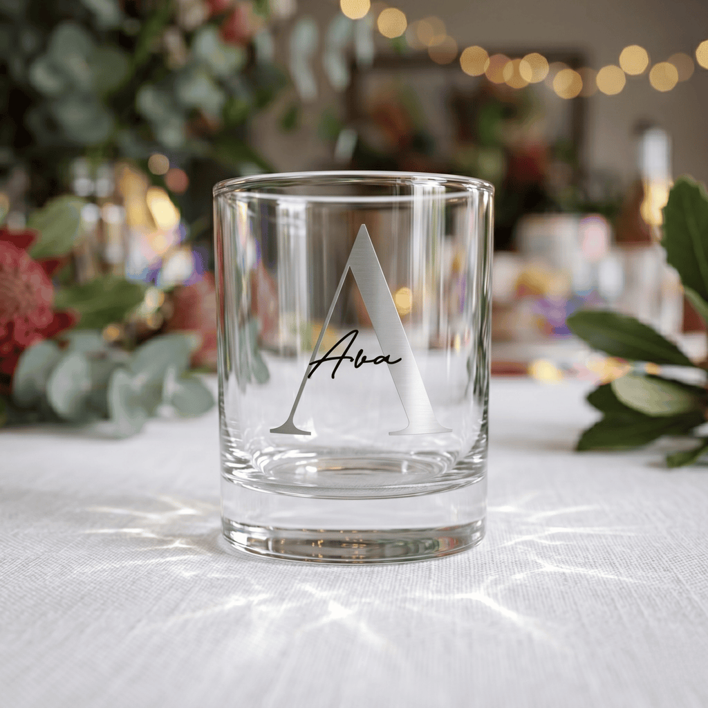 Clear glass with engraved letter 'A' and name on a white surface with decorative background