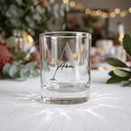 Clear glass with engraved letter 'A' and name on a white surface with decorative background