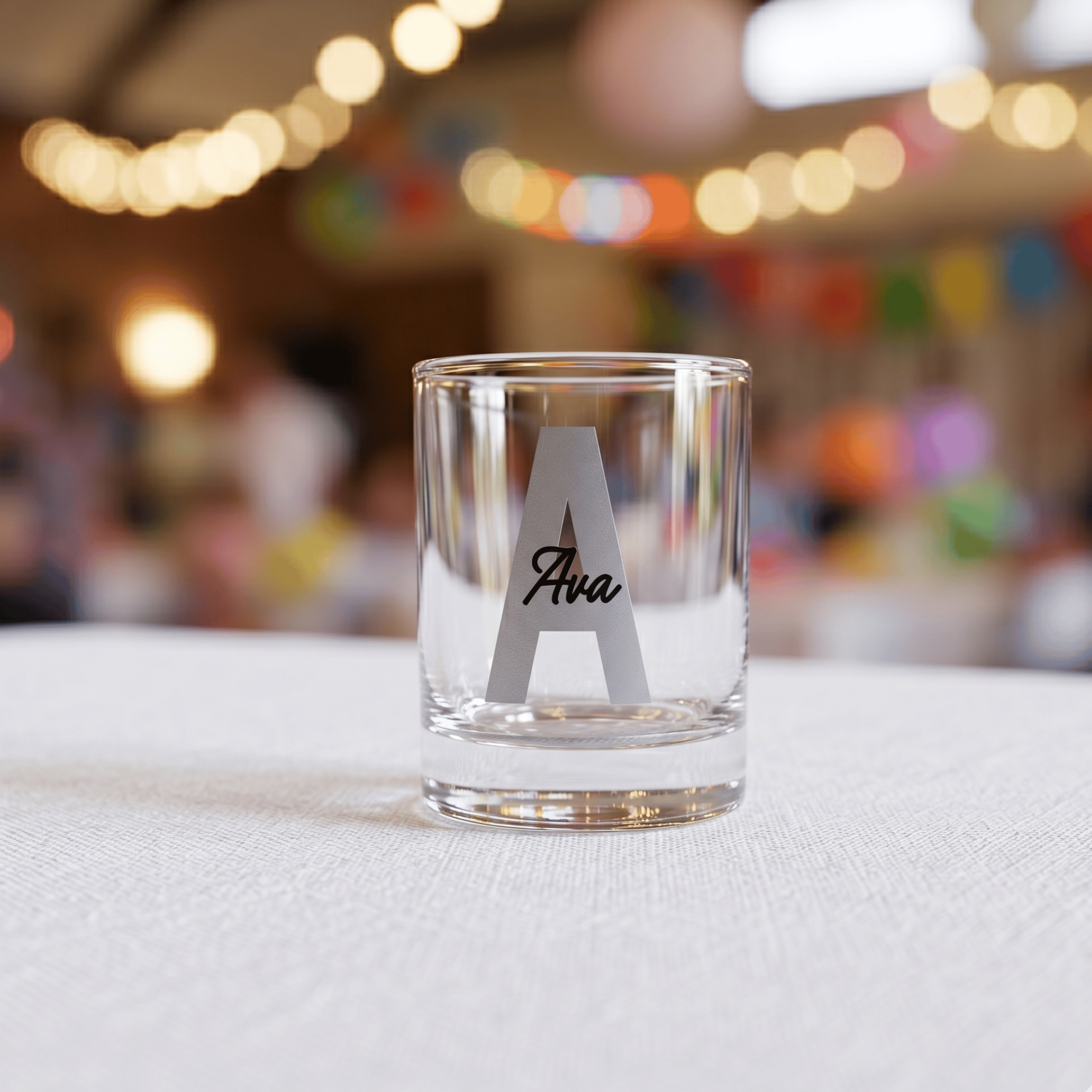 Clear glass with 'Ava' engraving on a white surface with blurred festive background