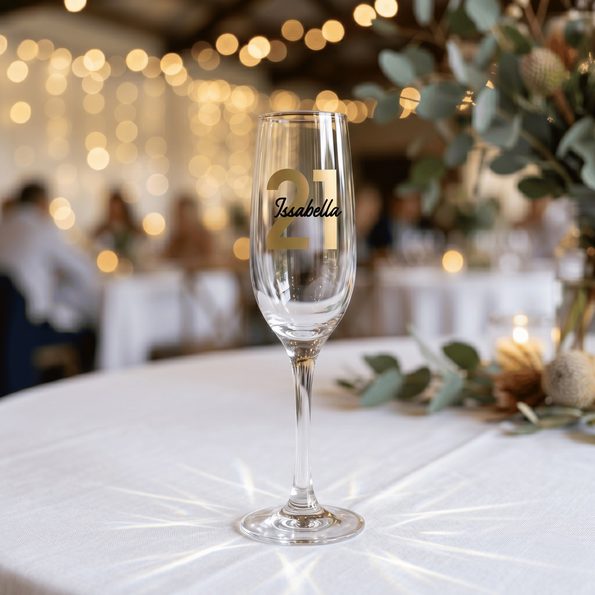 Champagne flute with '21 Isabella' on a table with blurred background