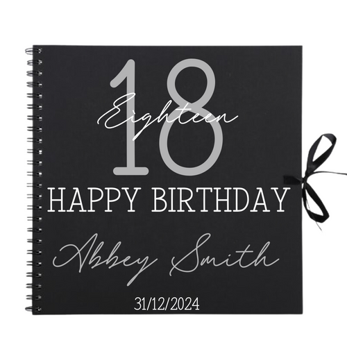 Close-up of 18th birthday personalised scrapbook album in black with ribbon tie, name and date on cover