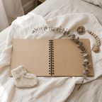 Open Album with a knitted bootie and decorative branch on a soft fabric surface