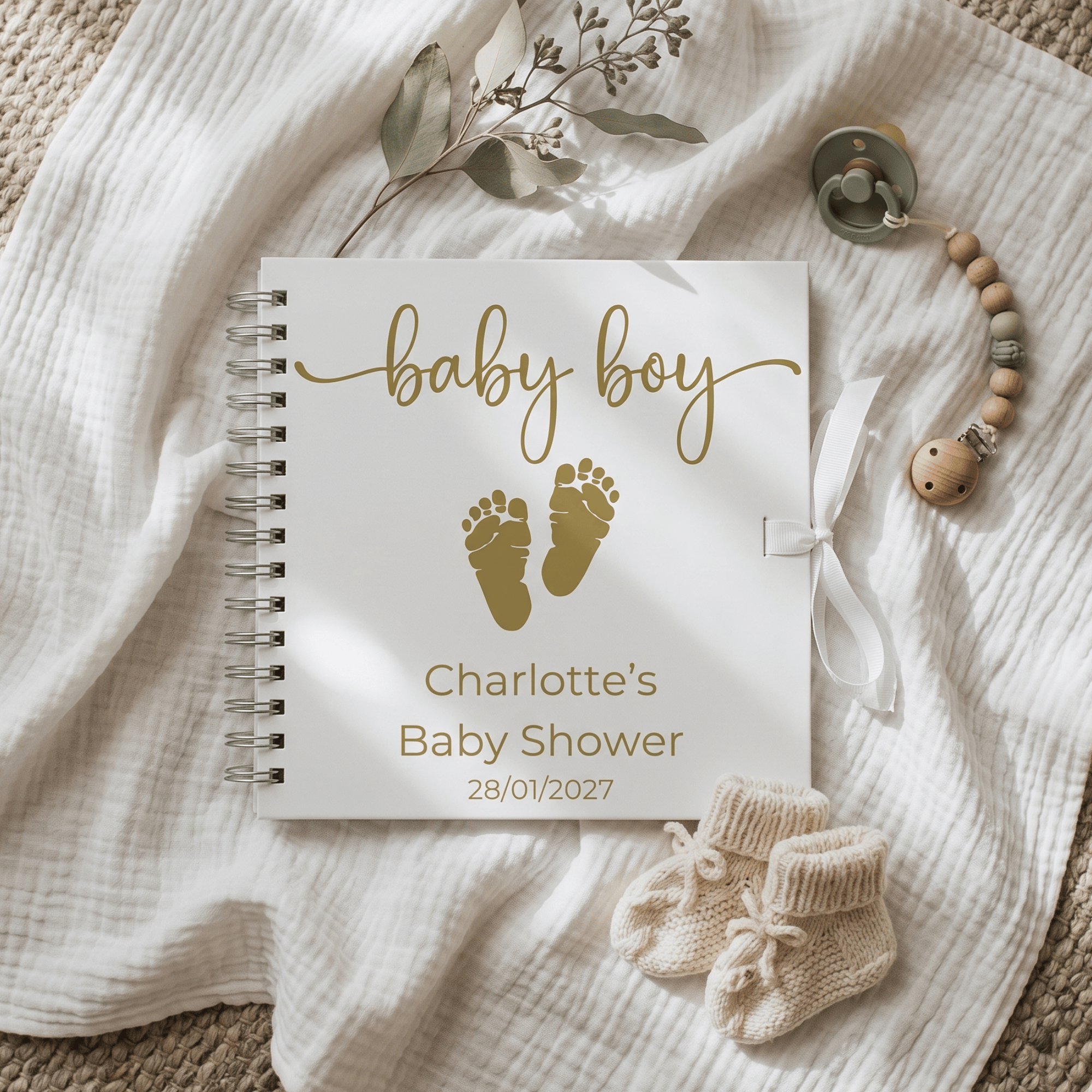 Baby shower Album with gold text and baby items on a textured fabric background