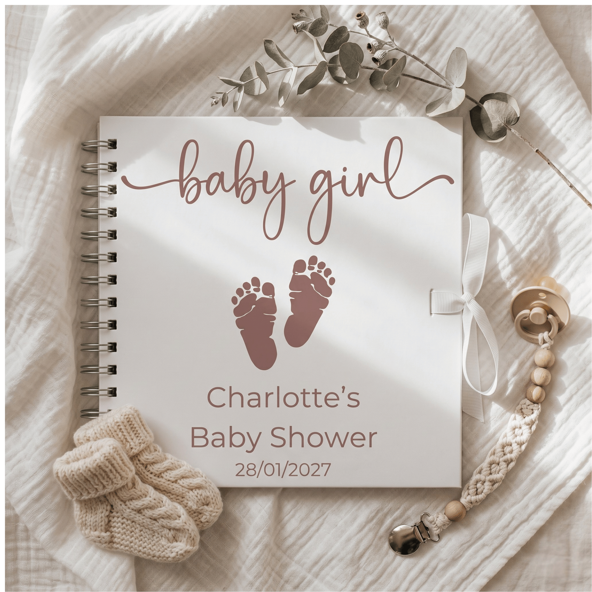 Baby shower guest book with 'baby girl' text and footprints on a soft fabric background.