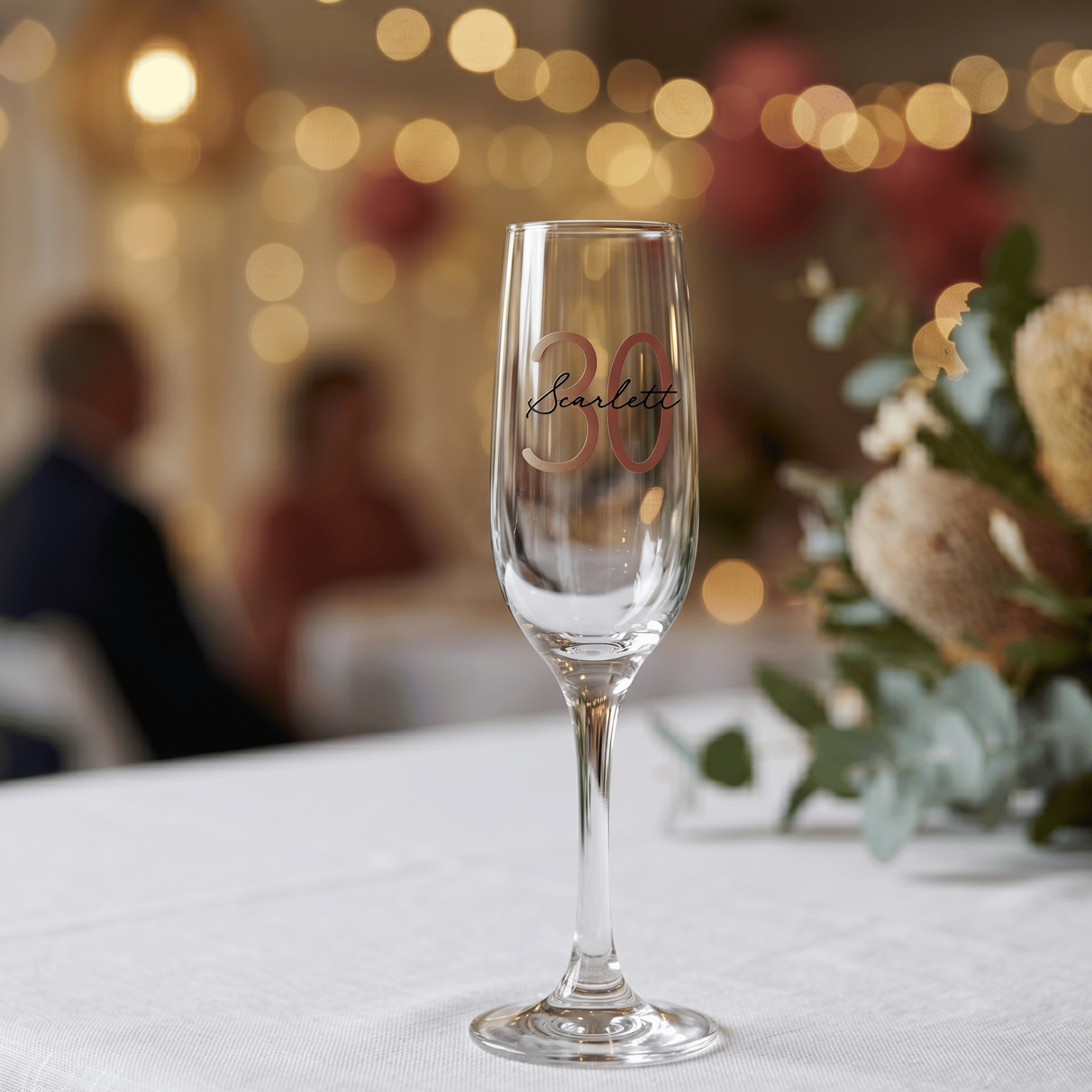 Champagne flute with '30 Scarlett' text on a blurred festive background