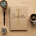 Notebook with 'Isabella' on a wooden surface with stationery items