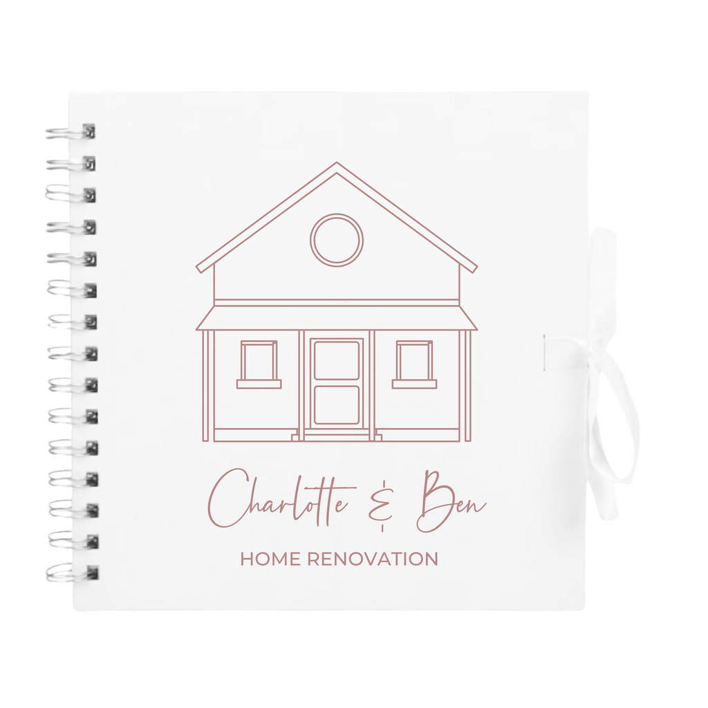 White scrapbook album with rose gold outline and custom text "Home Renovation", tied with white ribbon