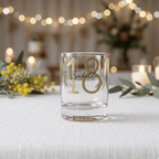 Clear glass with gold number '18' and name on a table with decorative elements