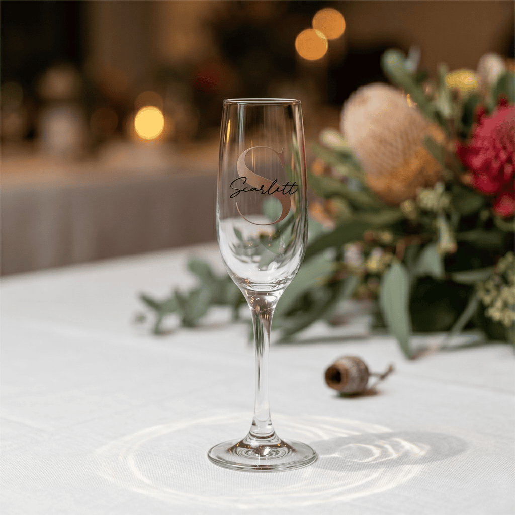 Champagne flute with 'Scarlett' engraving on a table with floral decorations