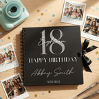 Black spiral-bound Album with '18 Happy Birthday Abbey Smith' on a wooden surface with photos and a camera.