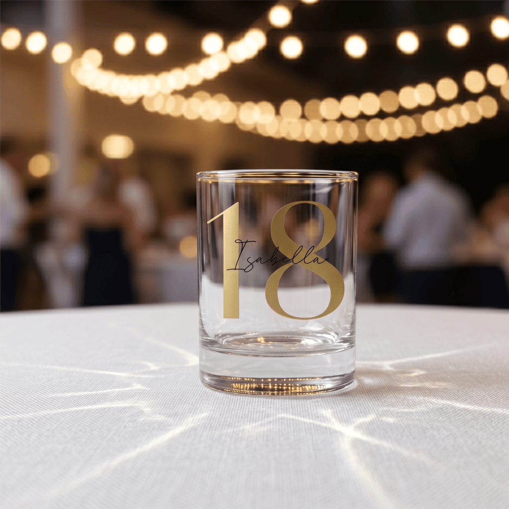 Glass with '18 Isabella' on a tablecloth with blurred lights in the background