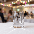 Clear glass with '21 Ava' engraving on a white tablecloth with blurred festive background