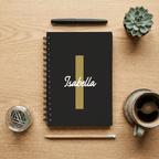 Black notebook with 'Isabella' on a wooden surface with stationery items.