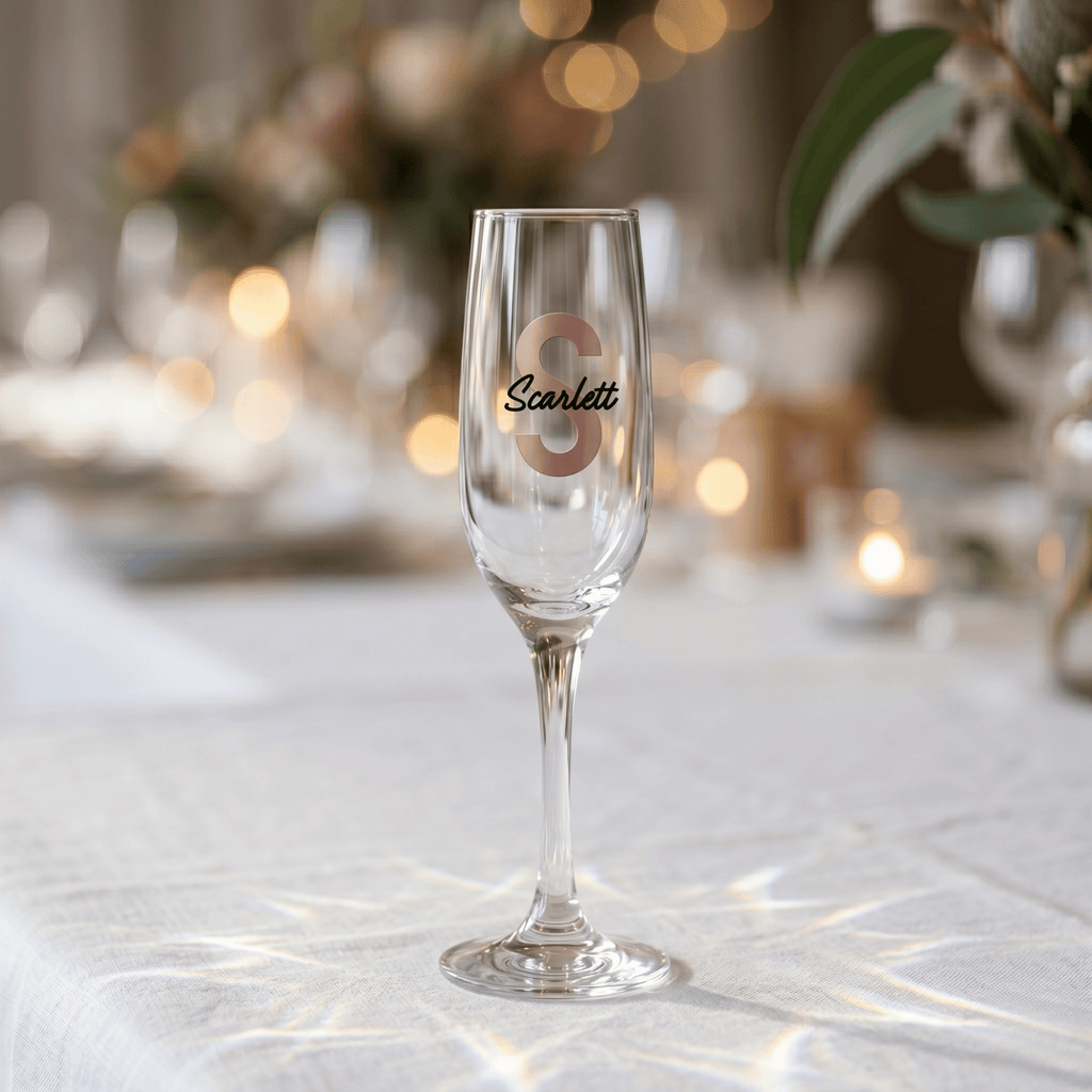 Champagne flute with 'Scarlett' engraved on a table with blurred lights and decorations