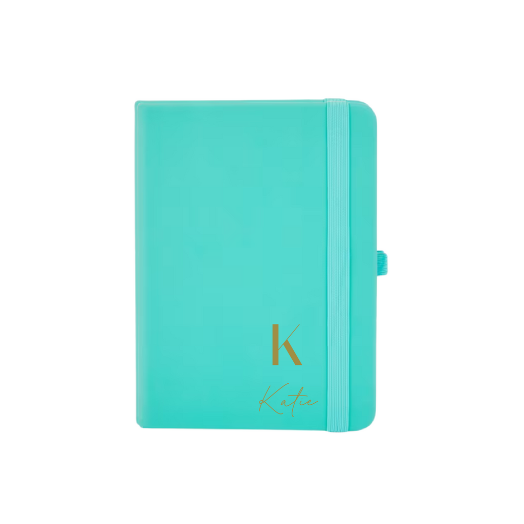 Personalised teal A6 vegan leather notebook with initial K and name Katie embossed on the cover.