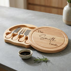 Personalised wooden serving set on a grey countertop, including a round engraved wooden lid with the text 'The Smith family' and a matching wooden tray holding three small knives with wooden handles.