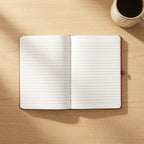 Custom laser engraved corporate notebook in black vegan leather with a metallic pen, displayed on an executive timber desk in a bright office.
