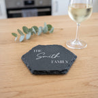 Close up of custom laser engraving on a dark geometric slate coaster showing traditional classic lettering and chipped edges.