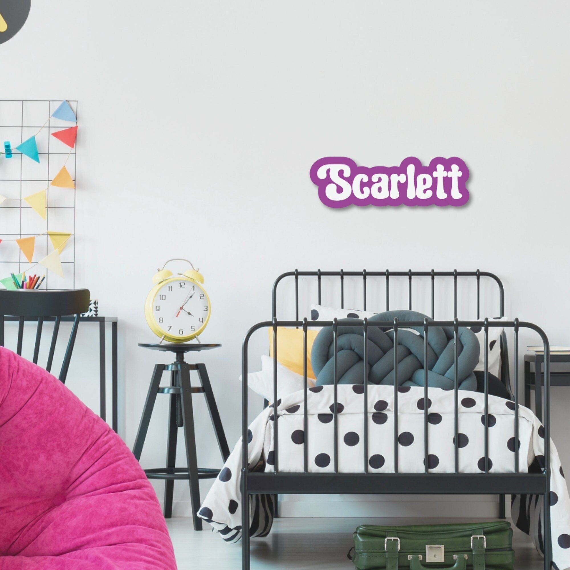 Personalised acrylic name plaque in purple reading 'Scarlett' displayed above a child's bed in a modern kids bedroom