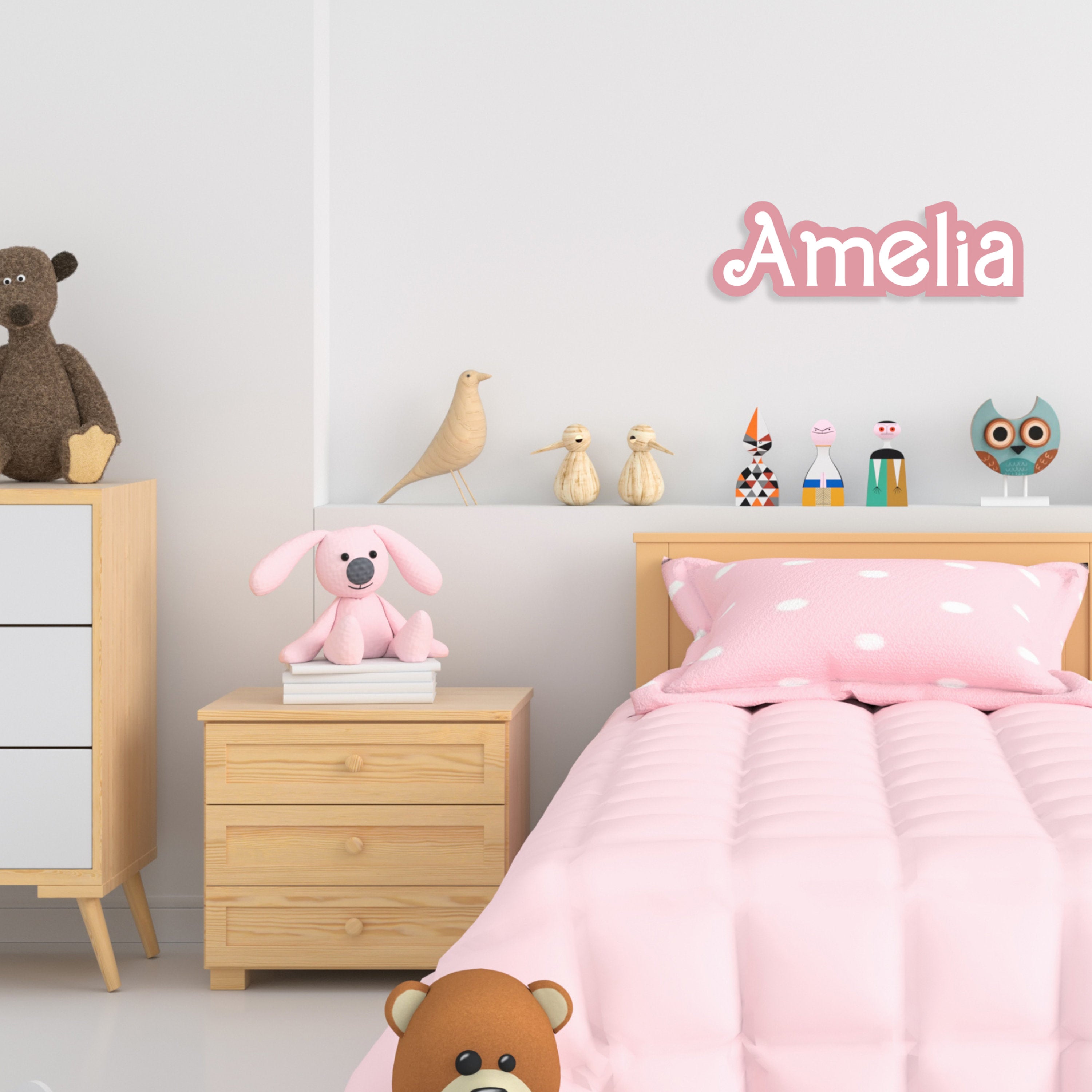 Custom acrylic kids name sign in pink saying 'Amelia' mounted above a bed
