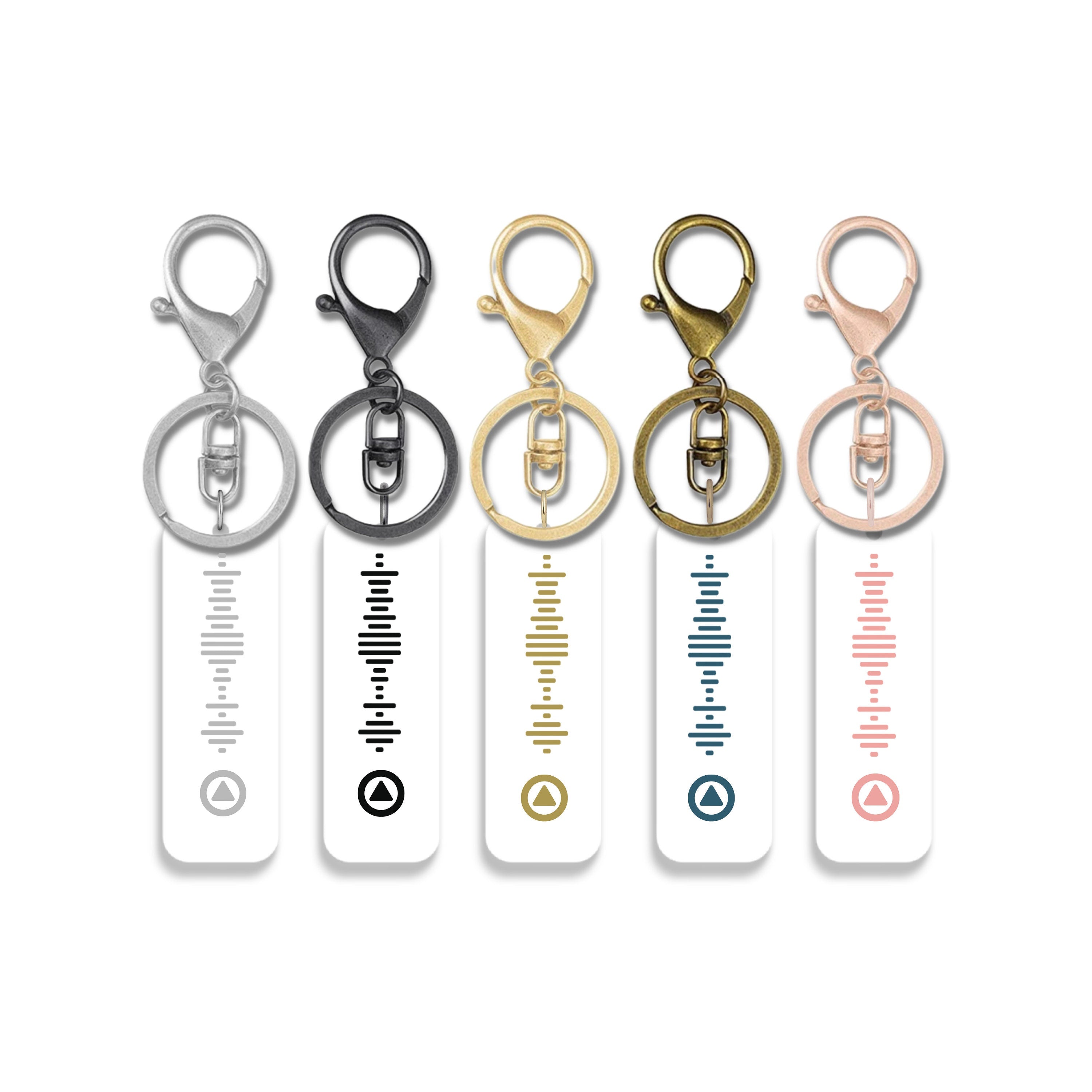 Set of five white acrylic music QR code keychains with Spotify-style designs and hardware in silver, gunmetal, gold, antique gold, and rose gold.