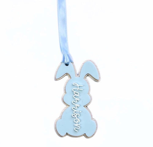 Personalised blue Easter bunny tag with name "Harrison" in white script – acrylic bunny-shaped basket tag with satin ribbon.