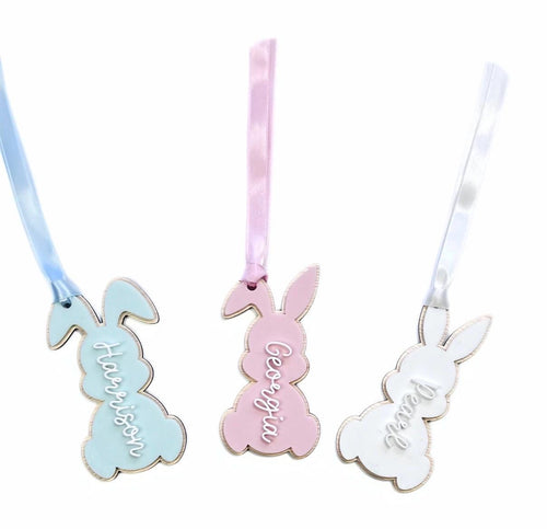 Set of three personalised Easter bunny tags in pastel blue, pink, and white – names "Harrison", "Georgia", and "Pearl" in script font with satin ribbons.