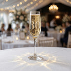 Champagne glass with '30' on a tablecloth in a festive indoor setting