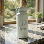 Light green water bottle with butterfly design and 'Peyton' text on a kitchen counter.