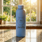 Blue water bottle with a cartoon character and 'Jordan' text on a table with a window in the background