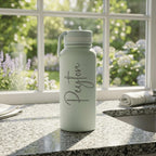 Light green water bottle with 'Peyton' on a kitchen counter with a window in the background