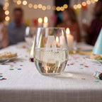 Clear glass with engraved name on a table with blurred people and lights in the background