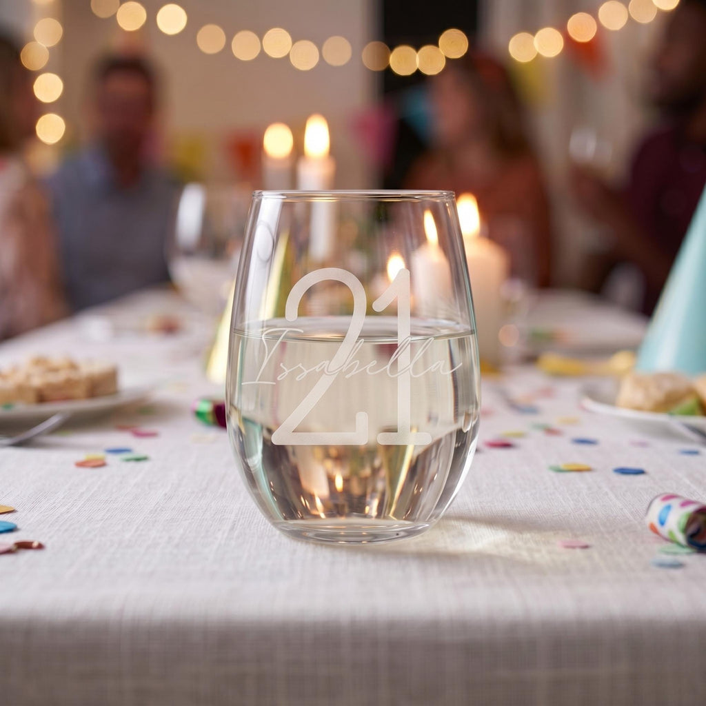 Glass with '21' on a table with blurred people and lights in the background