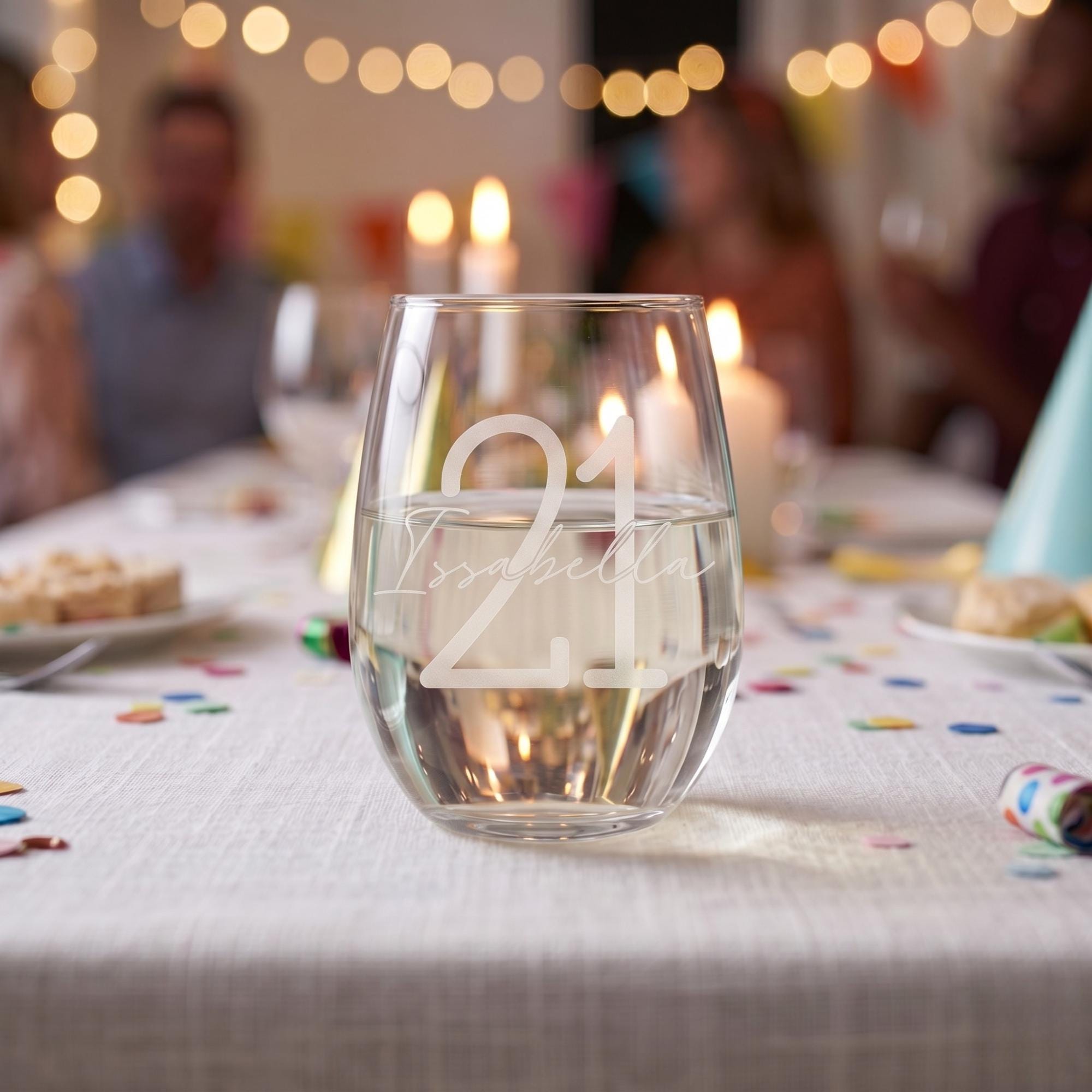 Glass with '21' on a table with blurred people and lights in the background