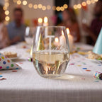 Personalized wine glass on a festive table with blurred people in the background