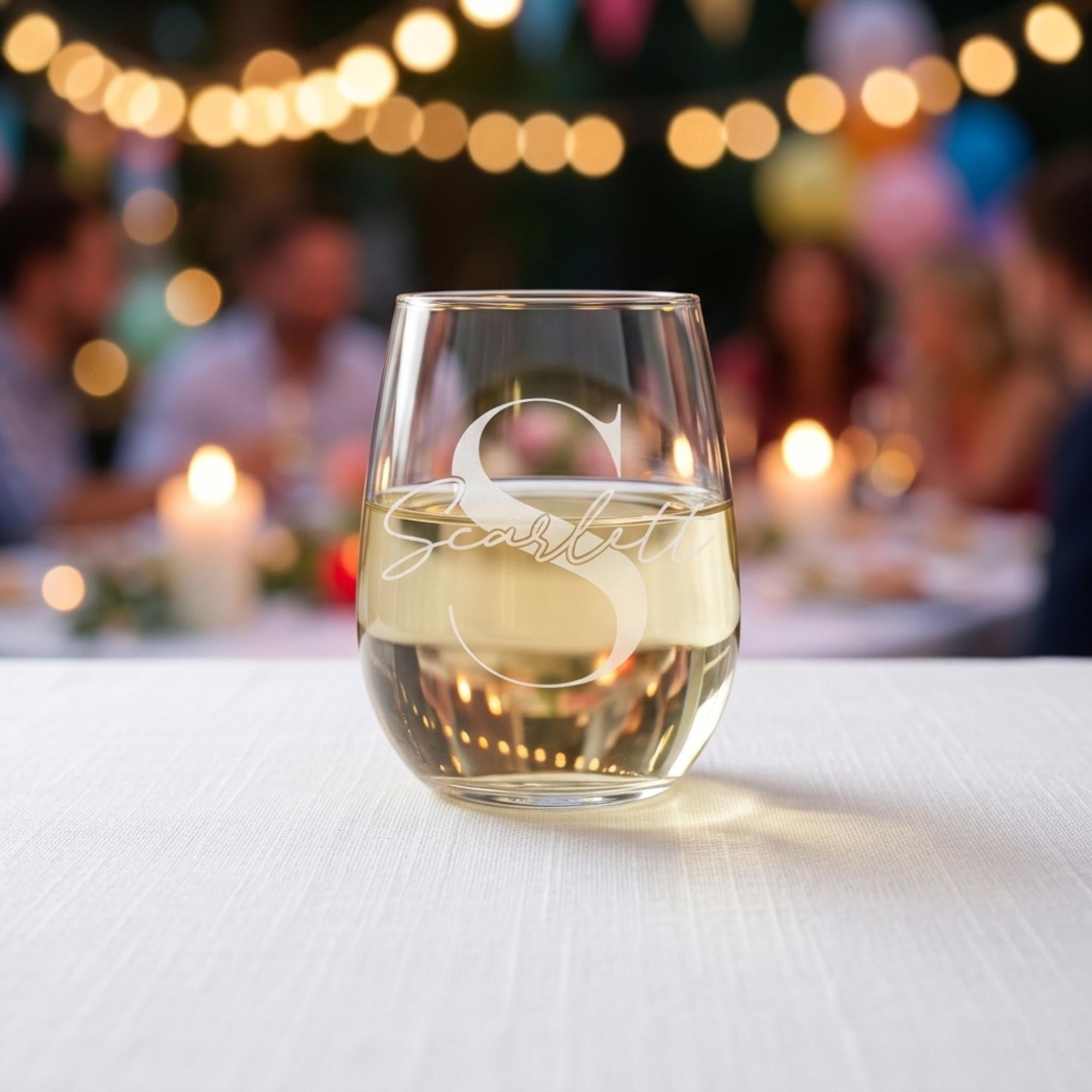 Glass of white wine with 'S Scarlett' branding on a table with blurred people and lights in the background