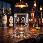 Clear glass with '18 Scarlet' engraving on a bar counter with tequila bottles and bar equipment.