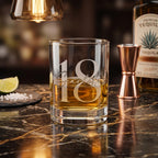 Glass with '18 Scarlet' engraving on a bar counter with tequila bottle and lime wedge.