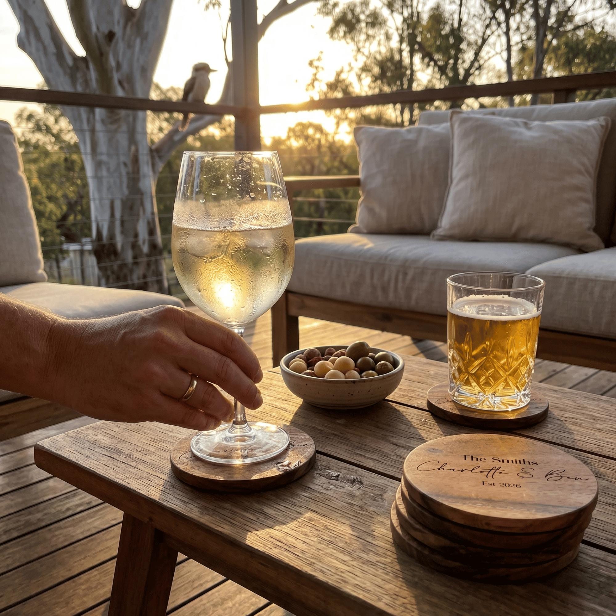 Person holding a glass of white wine on a wooden table with a sunset view