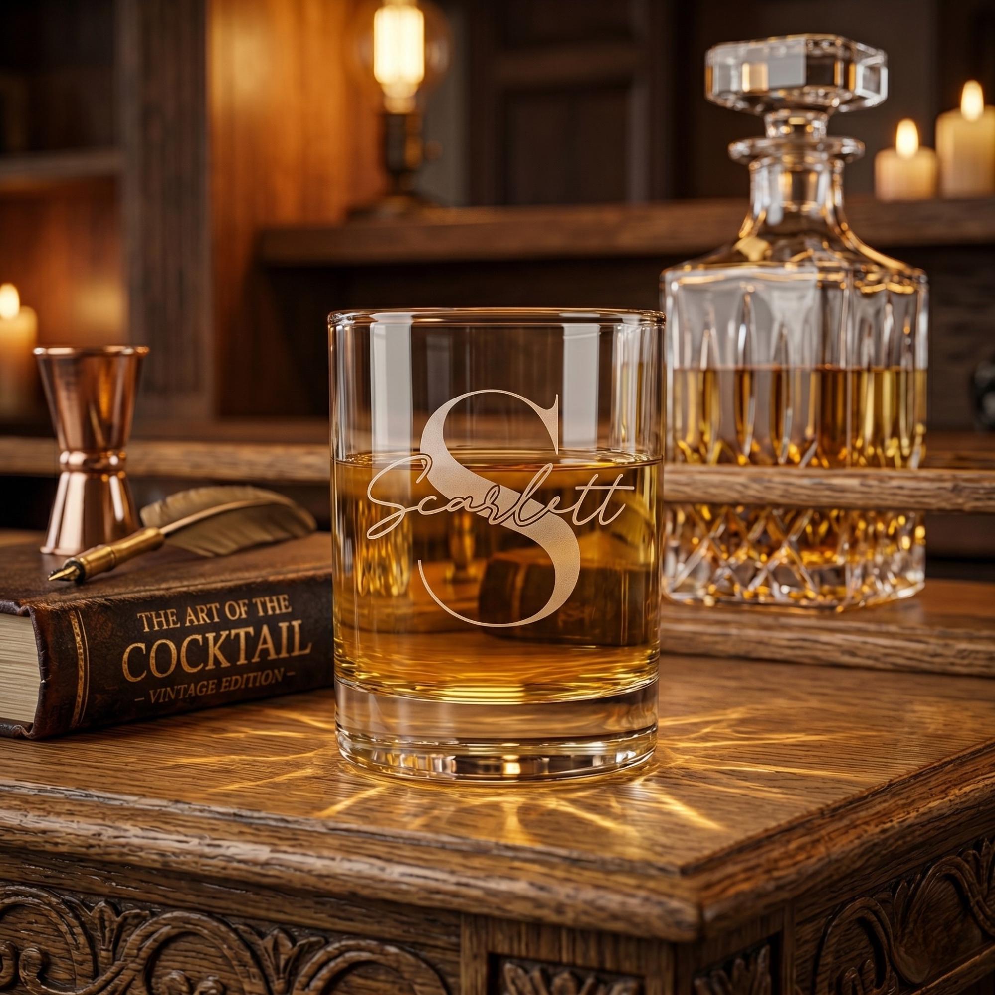 Glass of whiskey with 'Scarlett' branding on a wooden surface with a decanter and book in the background.